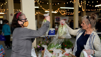 Sandy Meir, left, buys produce from Debby Taylor while wearing a mask at the Farmers Public Market in Oklahoma City, Oklahoma, U.S.