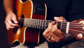 Photo of a person playing an accoustic guitar.