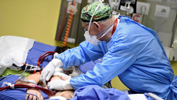 A member of the medical staff in a protective suit treats a patient suffering from coronavirus disease (COVID-19) in an intensive care unit at the San Raffaele hospital in Milan