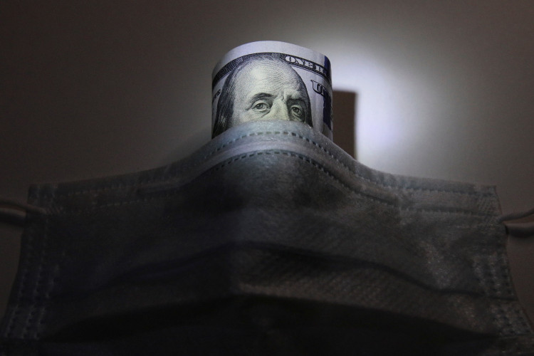 A U.S. dollar banknote is pictured behind a protective mask, which is widely used as a preventive measure against the coronavirus (COVID-19)