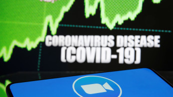 Zoom logo is seen in front of displayed coronavirus disease (COVID-19)