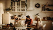 Family sits on table inside kitchen.