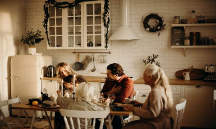 Family sits on table inside kitchen.