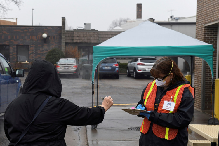 An election official takes a voter's driver's license information during the presidential primary election held amid the coronavirus disease (COVID-19) outbreak in New Richmond