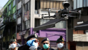 A police officer points at a drone, which is used by Malaysian police to remind citizens to stay at home