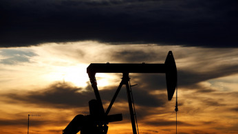 FILE PHOTO: The sun sets behind a crude oil pump jack on a drill pad in the Permian Basin in Loving County