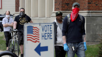 Patrick Kapple, right, waits in line outside Riverside University High School to cast a ballot during the presidential primary election held amid the coronavirus disease (COVID-19) outbreak in Milwaukee, Wisconsin