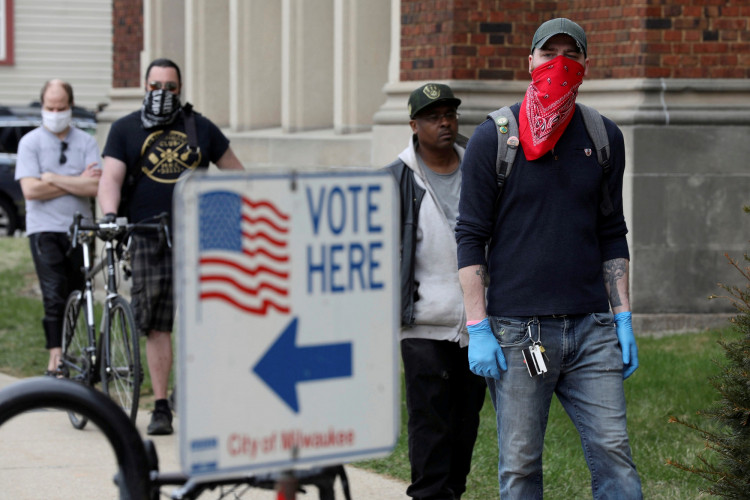Patrick Kapple, right, waits in line outside Riverside University High School to cast a ballot during the presidential primary election held amid the coronavirus disease (COVID-19) outbreak in Milwaukee, Wisconsin