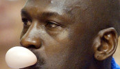 FILE PHOTO: Washington Wizards' Michael Jordan blows a bubble while sitting on the bench during a National Basketball Association game against the Philadelphia 76ers