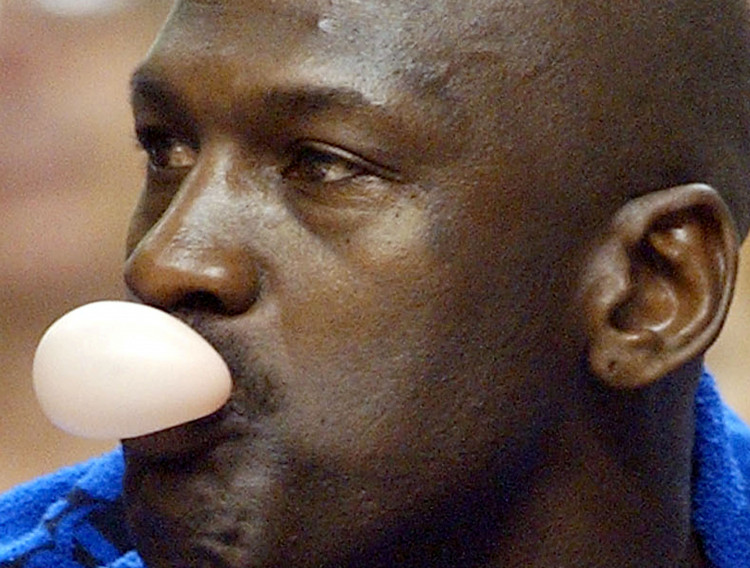 FILE PHOTO: Washington Wizards' Michael Jordan blows a bubble while sitting on the bench during a National Basketball Association game against the Philadelphia 76ers