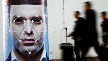 People walk past a poster simulating facial recognition software at an exhibition in Beijing, China 