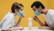 Couple wearing face mask drinking milkshake.