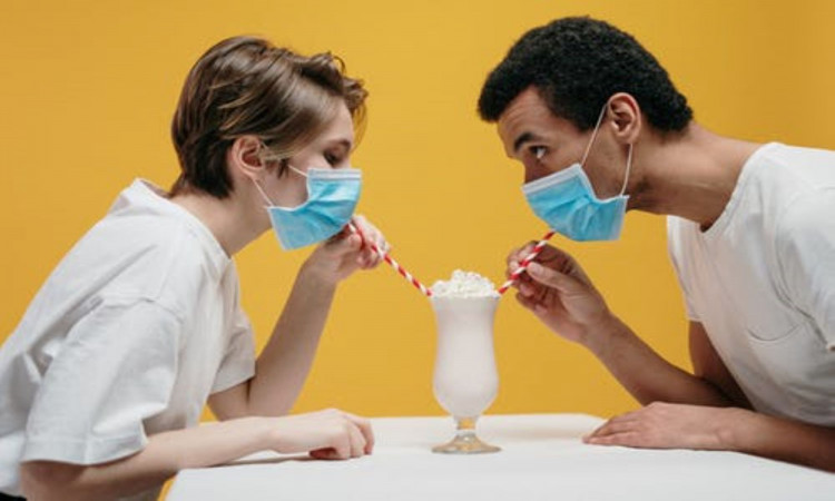 Couple wearing face mask drinking milkshake.