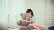 Woman hugging gray bear.