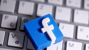 A 3D-printed Facebook logo is seen placed on a keyboard in this illustration