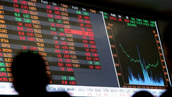FILE PHOTO: People look at an electronic board showing the graph of fluctuations of market indices at the floor of Brazil's BM&F Bovespa Stock Market in downtown Sao Paulo