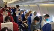 A flight attendant assists a passenger to fill in his travel history following the coronavirus disease (COVID-19) outbreak, on a China Eastern Airlines flight at Shenzhen Baoan International Airport in Shenzhen