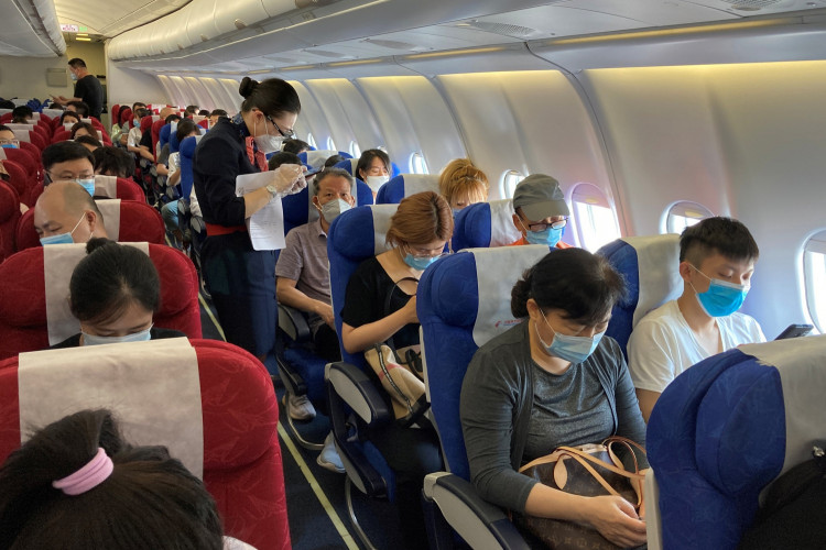 A flight attendant assists a passenger to fill in his travel history following the coronavirus disease (COVID-19) outbreak, on a China Eastern Airlines flight at Shenzhen Baoan International Airport in Shenzhen