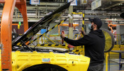 An operator at FCA's Brampton Assembly Plant installs a removable plexiglas partition in the engine compartment of a Dodge Challenger to help staff maintain social distancing against the coronavirus disease