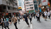 Anti-government protesters run after riot police disperse them in Hong Kong