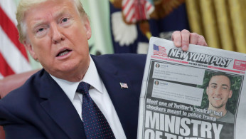 U.S. President Donald Trump holds up a front page of the New York Post as he speaks to reporters while discussing an executive order on social media companies in the Oval Office of the White House in Washington
