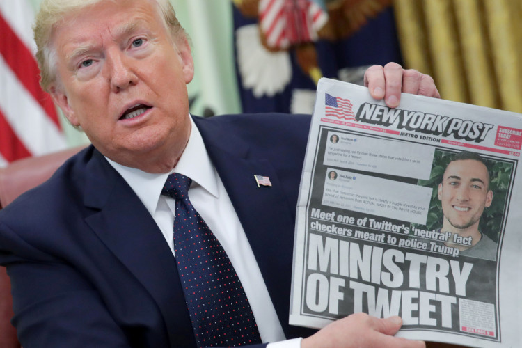 U.S. President Donald Trump holds up a front page of the New York Post as he speaks to reporters while discussing an executive order on social media companies in the Oval Office of the White House in Washington