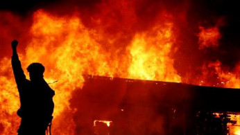 A protester gestures in front of a fire during a demonstration against the deathy of African-American man George Floyd