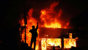 A protester gestures as buildings burn during continued demonstrations against the death in Minneapolis police custody of African-American man George Floyd