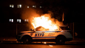 A NYPD police car is set on fire as protesters clash with police during a march against the death in Minneapolis police custody of George Floyd