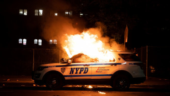 A NYPD police car is set on fire as protesters clash with police during a march against the death in Minneapolis police custody of George Floyd