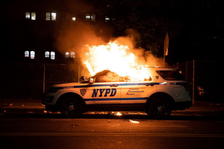 A NYPD police car is set on fire as protesters clash with police during a march against the death in Minneapolis police custody of George Floyd