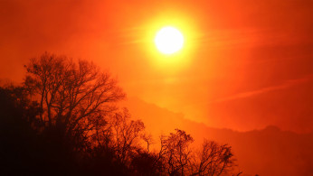 The sun rises over a smoldering landscape that was burned by a wildfire dubbed the Cave Fire, burning in the hills of Santa Barbara, California