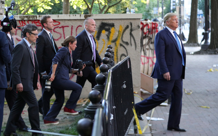 U.S. President Trump walks past a building defaced with graffiti by protestors in Washington