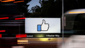 The entrance sign to Facebook headquarters is seen through two moving buses in Menlo Park