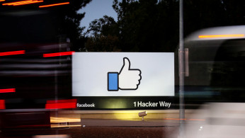 The entrance sign to Facebook headquarters is seen through two moving buses in Menlo Park