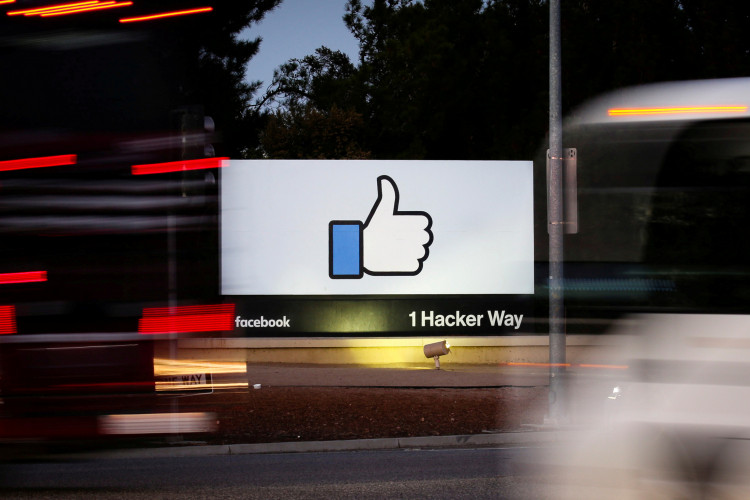 The entrance sign to Facebook headquarters is seen through two moving buses in Menlo Park