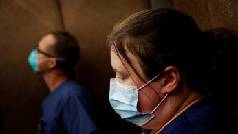 Traveling nurse Meghan Lindsey looks down wearing a protective face mask after her shift on Mother’s Day in her hotel elevator hotel in the Queens borough of New York