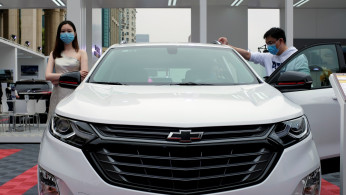 Model stands next to a Chevrolet vehicle at a sales event in Shanghai