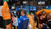 People dressed in food-themed costumes walk on the floor of the New York Stock Exchange to celebrate the IPO of GrubHub in New York 