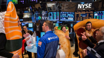 People dressed in food-themed costumes walk on the floor of the New York Stock Exchange to celebrate the IPO of GrubHub in New York 