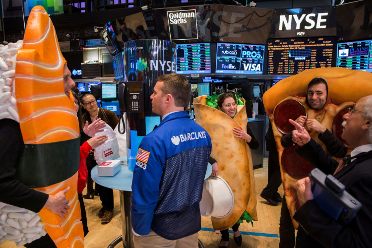 People dressed in food-themed costumes walk on the floor of the New York Stock Exchange to celebrate the IPO of GrubHub in New York 