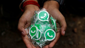 A WhatsApp-Reliance Jio representative displays keychains with the logo of WhatsApp for distribution during a drive by the two companies to educate users, on the outskirts of Kolkata