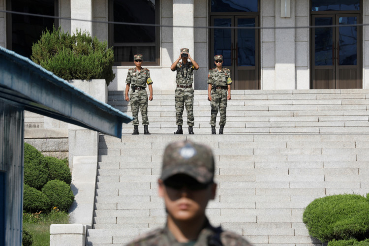  North Korean soldiers look toward the south as a South Korean soldier stands guard in the truce village of Panmunjom inside the demilitarized zone (DMZ) separating the two Koreas, South Korea, August 28, 2019. 