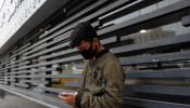 An Iranian young man wears a protective face mask, following the outbreak of the coronavirus disease (COVID-19), as he uses his smartphone 