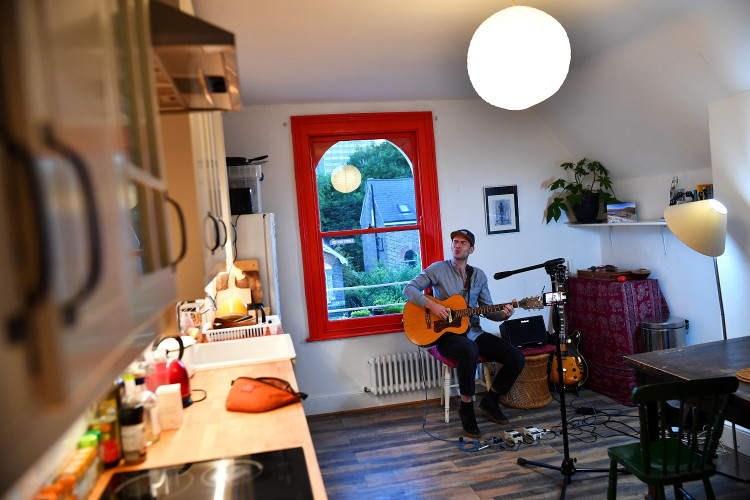 Musician Theo Bard sings as he performs an online gig from his kitchen in London