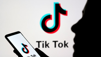 Person holds a smartphone with Tik Tok logo displayed in this picture illustration