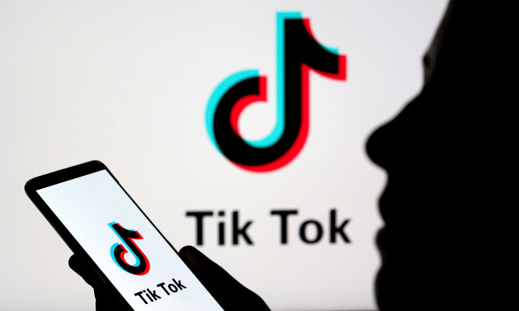 Person holds a smartphone with Tik Tok logo displayed in this picture illustration