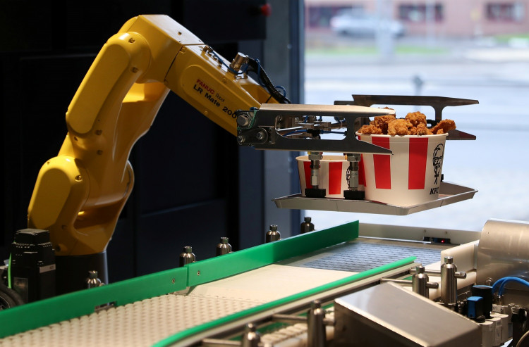 A robotic arm places a tray of food to a conveyor belt at a KFC restaurant offering contactless service