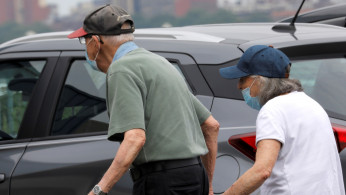 An elderly couple wear protective face masks outside at a shopping plaza
