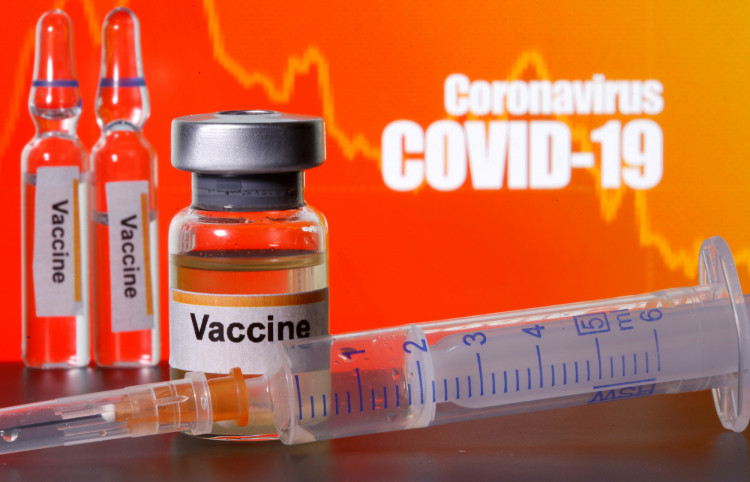  A woman holds a small bottle labeled with a "Vaccine COVID-19" sticker and a medical syringe in this illustration taken April 10, 2020.